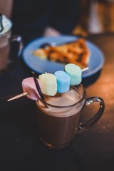 Hot chocolate drink with colored marshmallows and pie on the background 