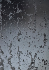 Close-up of a drop on the glass after rain and snow flowing down on a soft background