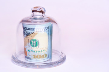 Banknotes worth one hundred dollars under a glass dome on a white background. Copy space.