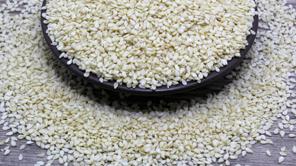 sesame seeds scattered on a plate on a wooden background