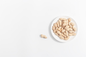 Peanuts on a white saucer. Top view.