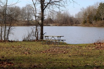 The empty picnic table on the shore of the lake.