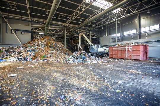 Excavator on primary sorting of garbage at waste processing plant. Separate garbage collection. Recycling and storage of waste for further disposal. Business for sorting and processing of waste.