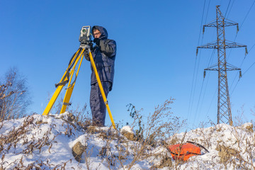 Surveyor in the winter on the construction site conducts topographic and cadastral work