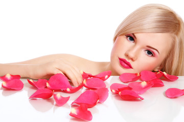Obraz na płótnie Canvas Young beautiful blonde healthy woman with rose petals over white background, copy space above