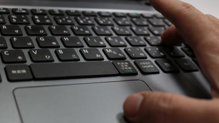 トラックパッド、キーボードを操作中のノートパソコン