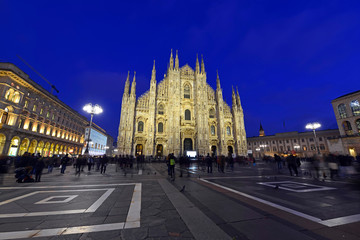 Fototapeta na wymiar Gothic architecture of Milan Cathedral at night in Milan Italy with purposely blurred unrecognizable crowd of people in square