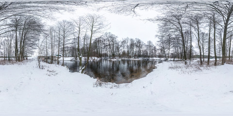 Winter full spherical seamless panorama 360 degrees angle view on road in a snowy park with gray pale sky near small river in equirectangular projection. VR AR content