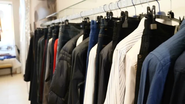 At clothes shop. Row of men and women clothing. jackets, jeans and shirts on hangers. Collection of new beautiful clothes hanging on hangers in a shop. New collection in fashion boutique. No people