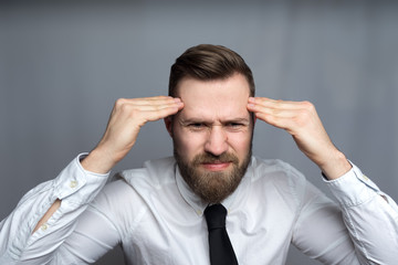 stressed young businessman sitting in office holding head