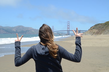 Segno della vittoria di ragazza dalla spiaggia al cospetto del Golden Gate 