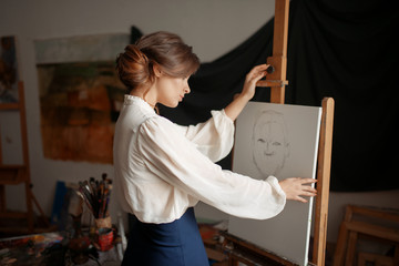 Cute female artist drawing in studio
