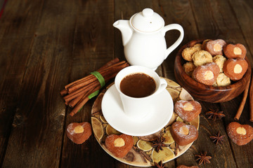 cup of coffee with a saucer and a white kettle with heart-shaped cookies on a rustic wooden table