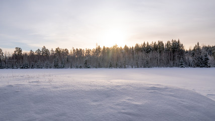 Fototapeta na wymiar Sunset over a field covered with snow. January 2019, Turku Finland.