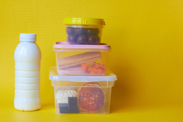 Food in plastic containers on a yellow background.