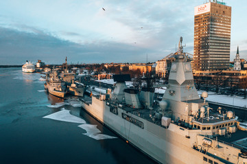 Riga, Latvia. January 10, 2019. Many warships docked at the port in the icy river. Aerial view of...