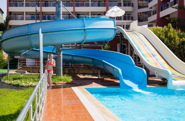 Obraz na płótnie Canvas Girl at the pool with slides at resort