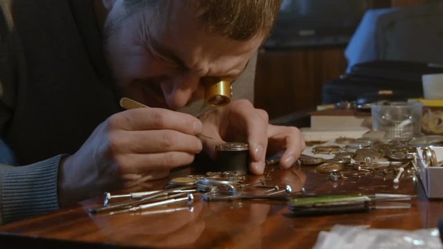 portrait of a watchmaker in a special magnifying eyepiece. Man repairing mechanical watches