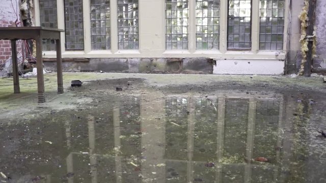 flooded ground outside stained glass window of old abandoned mansion