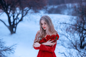 magical image of attractive blonde girl in gorgeous red dress decorated with flowers, Rose princess trying to keep warm in snowy forest, wonderful work of make-up by visagiste and photographer © kharchenkoirina