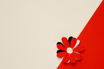 Flower made of red, white, black paper on border of white and red background. Minimal background to...