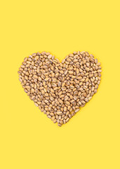 Heart of pistachios on a bright yellow background.