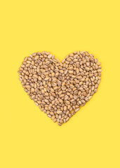 Heart of pistachios on a bright yellow background.