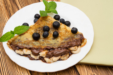 Homemade crepes served with fresh blueberries and powdered sugar on rustic wooden table