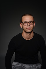 a man in a black jacket shows emotions in the Studio on a black background