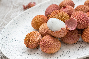 Fresh organic lychee fruit in a bowl on a rustic wooden background. Healthy vegan food concept. Close-up