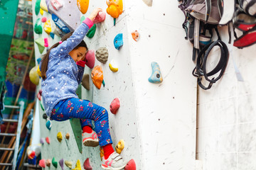 Little girl climbing a rock wall indoor