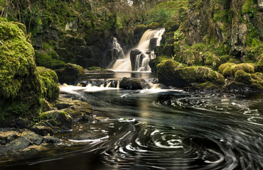 Long exposure shot of Linn Jaw Waterfall, near Livingston, Scotland, with white foam spiral swirls...