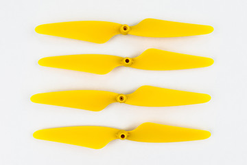 Yellow, plastic propellers for a quadcopter drone, isolated on white background with clipping path. Four pieces arranged in a row.