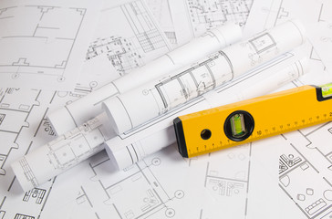 spirit level and paper еngineering house drawings and blueprints.