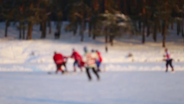 Anonymous defocused men playing hockey game outdoors using ice rink made on frozen river. Healthy lifestyle. Real time full hd video footage.
