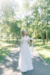 Fototapeta na wymiar The bride in a white dress in nature in the Park. Photo shoot with a bouquet in the style of fine art.