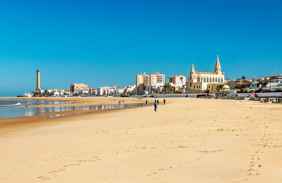 Chipiona, Cadiz, Spain-June 2016. Tourists walking along the beach of the turistic municipality of the coast of light in Cadiz on a sunny day.