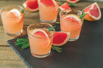 Alcoholic cocktail with grapefruit drink glass on a black stone board