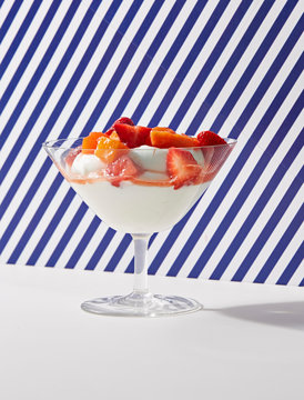 Yogurt in Glass with Strawberry and Peach Topping with Striped Background