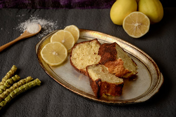 Classic lemon pound cake on rustic grey background with slices of lemon