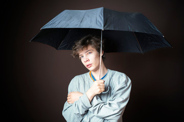 young sad man hold umbrella in bad weather on dark background b d