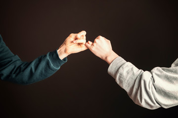 two men hold their little fingers and make peace d s