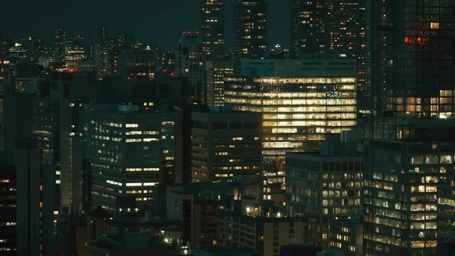 City skyscrapers at night with lights on. Telephoto lens from high up. Dark and moody with an epic feeling. Downtown big office buildings in a major city. 