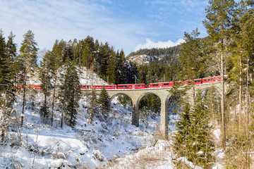 A red train passing on the Schmitten viaduct, near Landwasser Viaduct, Switezrland