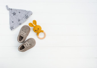 Newborn baby hat, shoes and rabbit beanbag on white wooden background