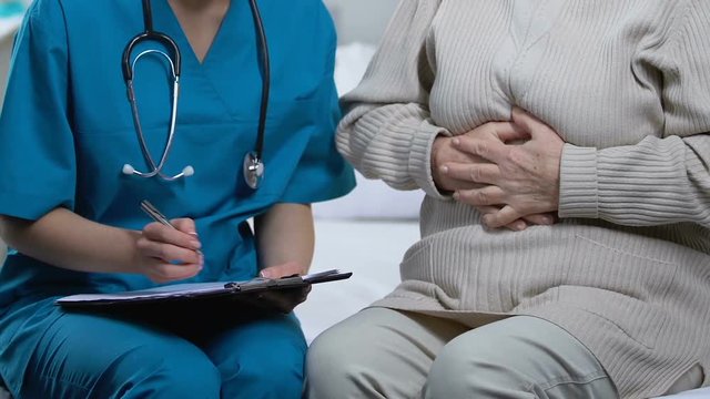 Senior female patient telling doctor about strong stomachache, calling ambulance