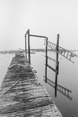 Obraz premium View on abandoned pier on a foggy morning black and white photo