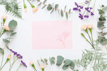 Flowers composition. Paper blank, carnation flowers, eucalyptus branches on pastel  background. Flat lay, top view, copy spaceFlat lay stiil life.