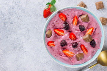 Eating healthy breakfast bowl. banana and blackberry smoothie, fresh strawberries in blue ceramic bowl
