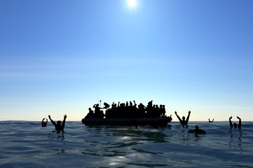 Profughi su un grande gommone in mezzo al mare che richiedono aiuto. Mare con persone in acqua che chiedono aiuto. Migranti che attraversano il mare - obrazy, fototapety, plakaty